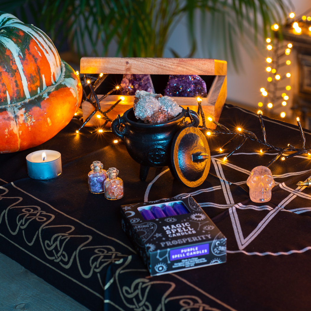 witches altar with gemstones, spell candles, and cauldron