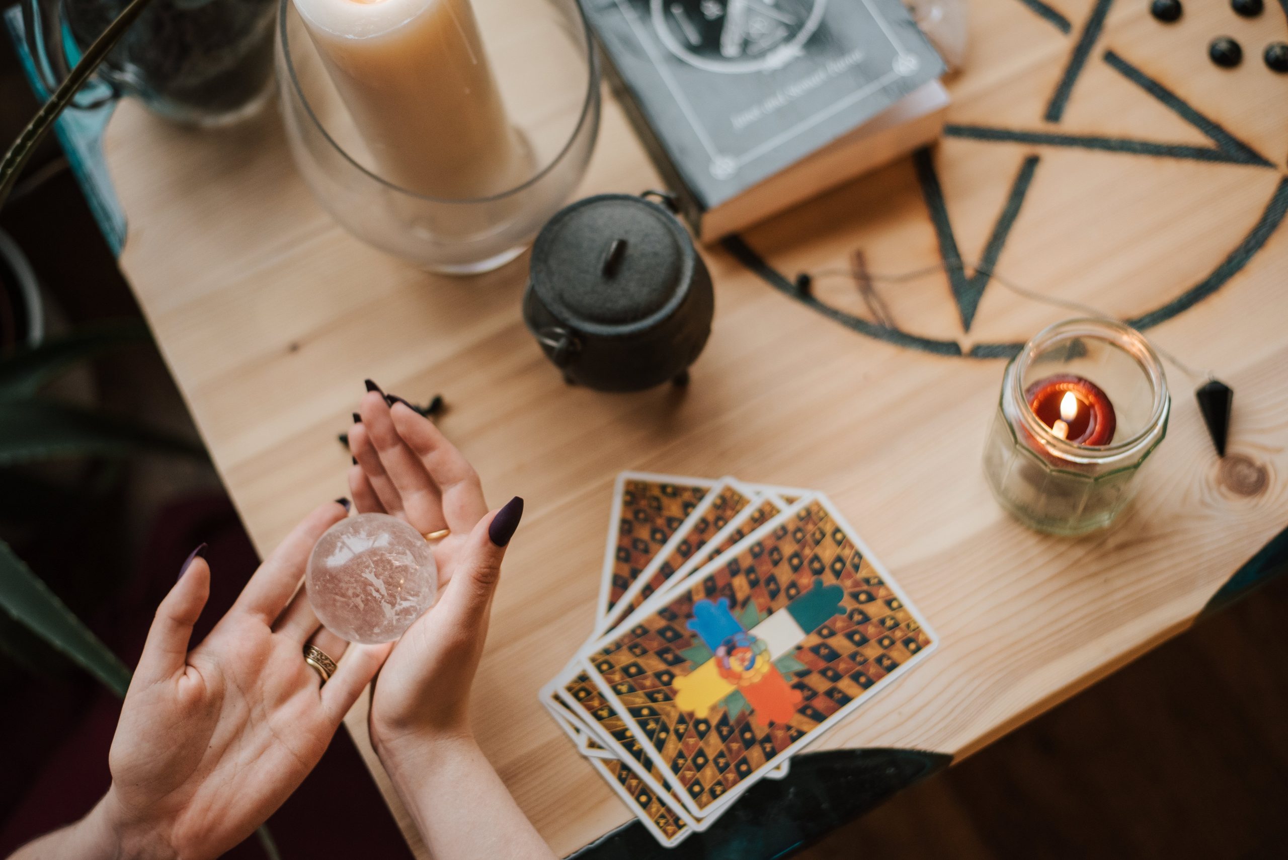 tarot cards, crystal ball, and cauldron on table