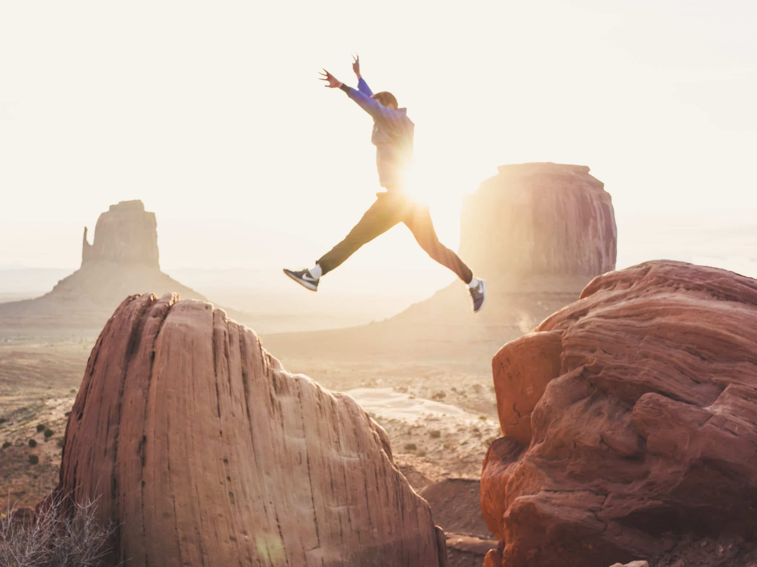 man leaping from boulder to boulder