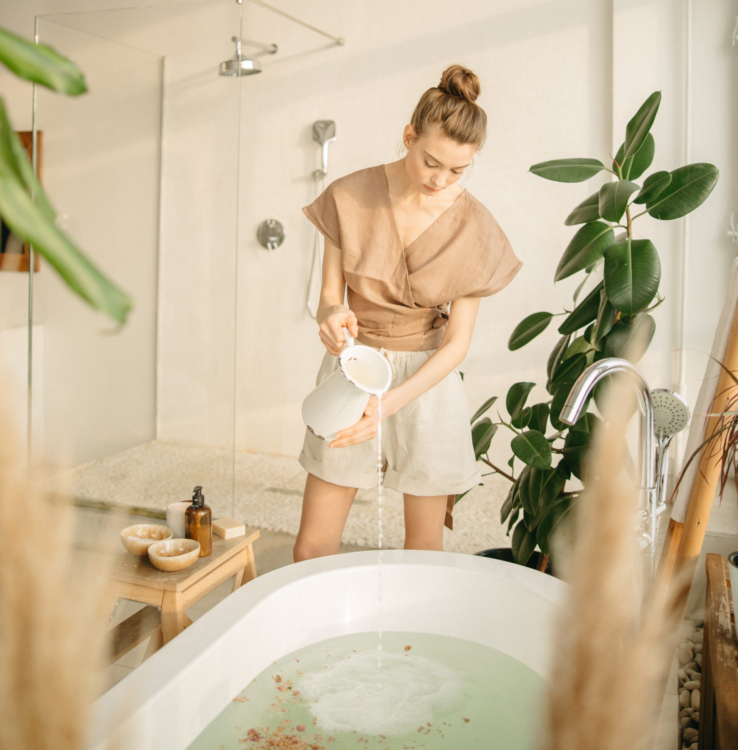 woman pouring water from pitcher into bath