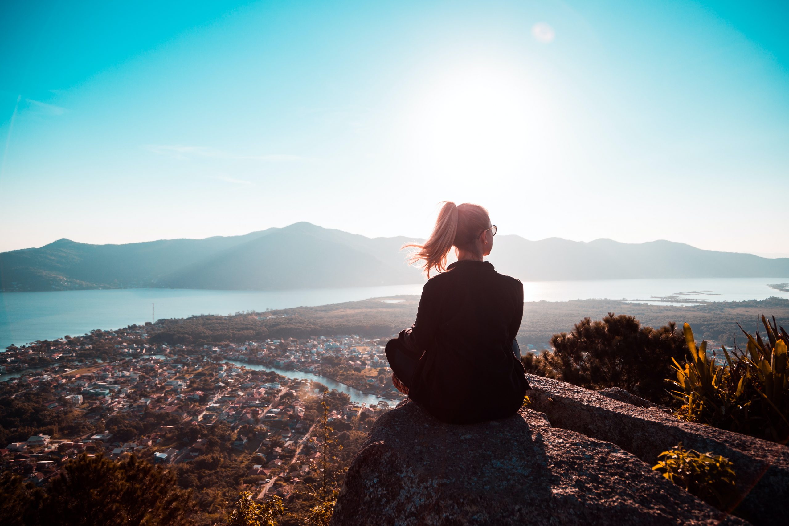 woman sitting by sea in sunlight