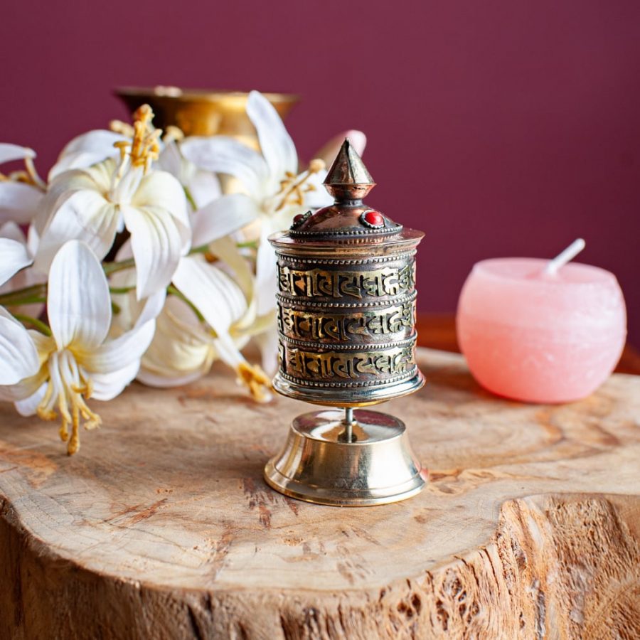 tibetan prayer wheel on wooden table white flowers
