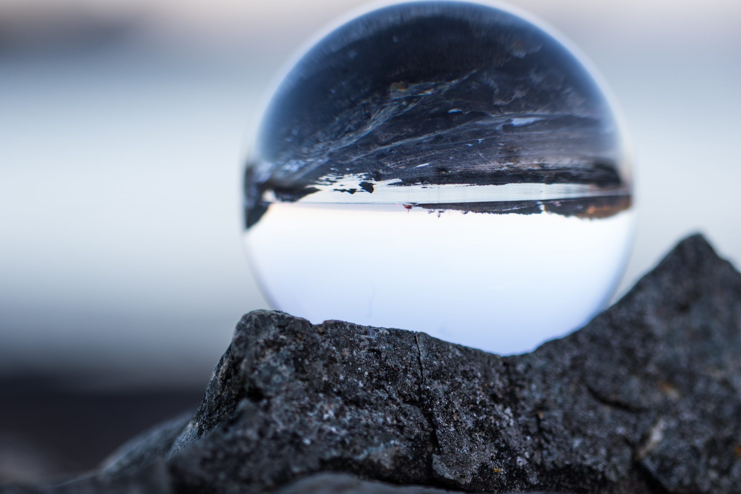 glass ball photography gray coast rocks water
