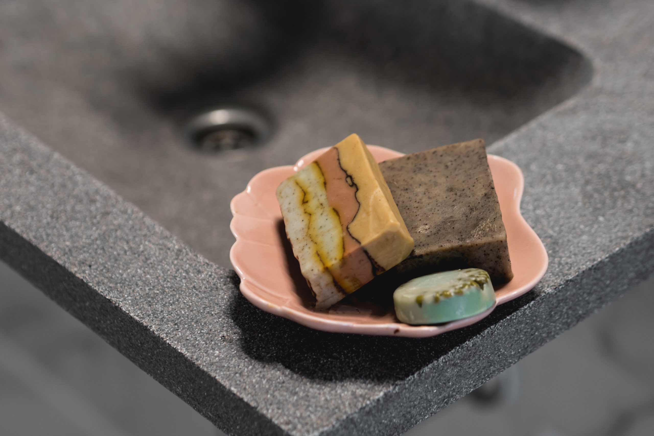 organing homemade soaps in bathroom on pink ceramic dish
